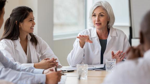 Doctor conducting meeting with her coworkers.